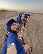 Brynli riding on a camel in the desert