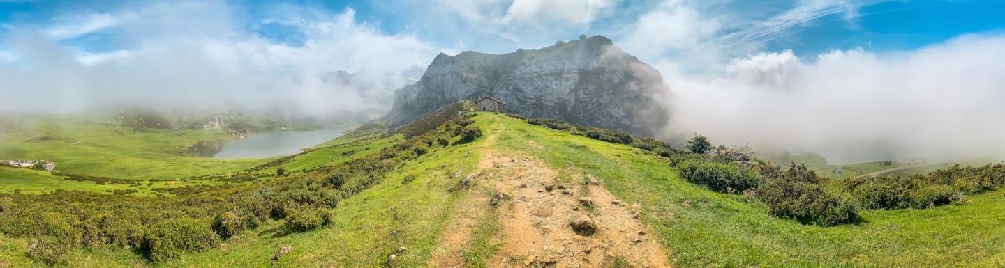 Dirt pathway leading to a small house on a grassy hill