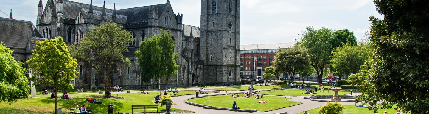 Grassy area and seating area in front of grey-brick cathedral