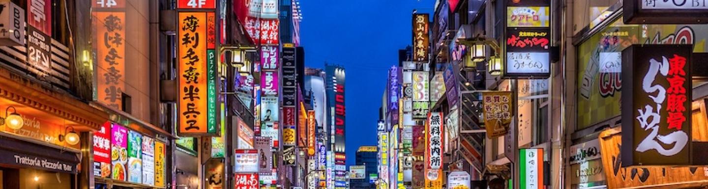 A bustling street in Tokyo with neon signs on buildings