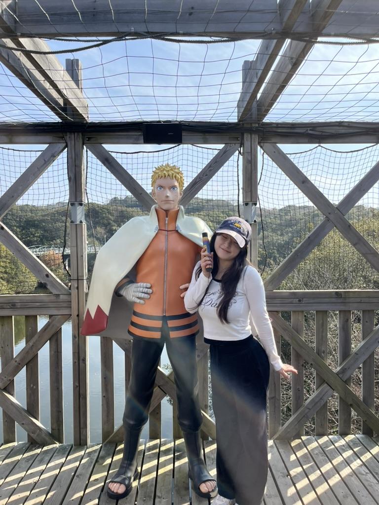 girl standing next to naruto in japan