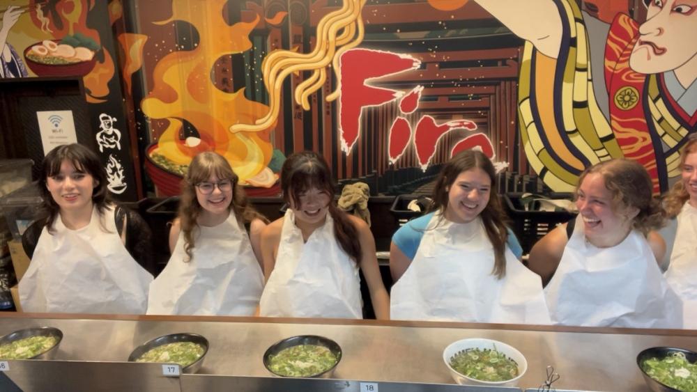Four college students sitting in a ramen shop in Japan.