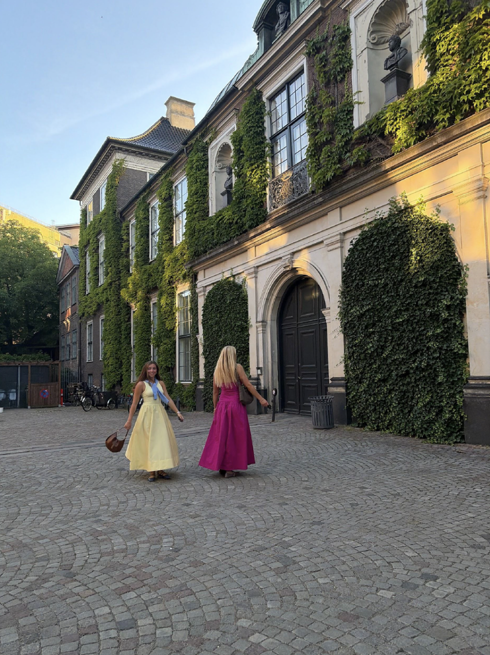 Two students standing in front of a building with ivy on it