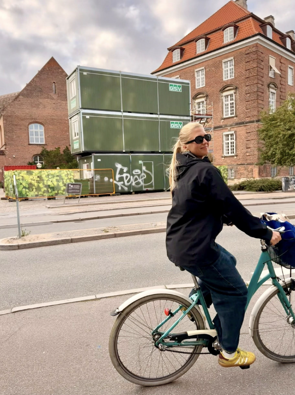 A student riding a blue bike through a street