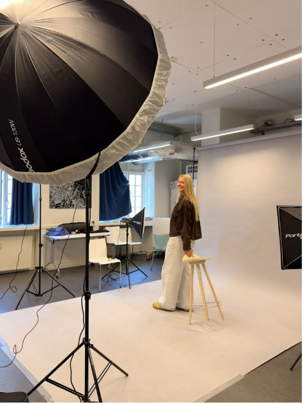 A student holding a white chair in a photostudio