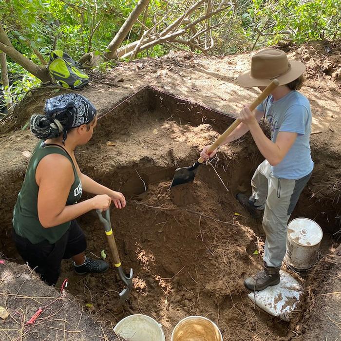 two students digging in an excavation site in Barbados