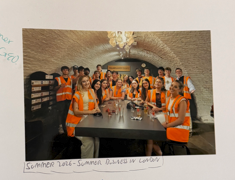 A group of UO students sitting around a table in orange vests