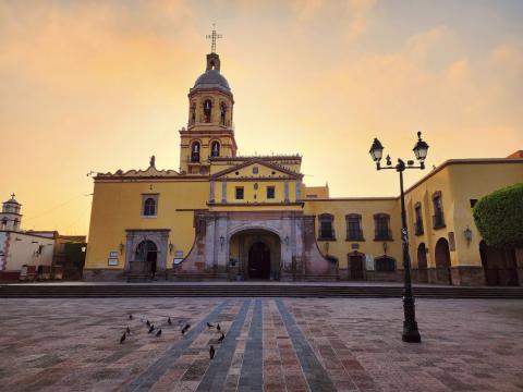A yellow church with a yellow sunset behind it