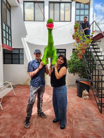 Alex standing with his host mom and a floating green dinosaur pinata