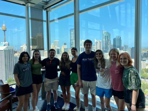 Group of college students smiling in front of a large building window in Australia