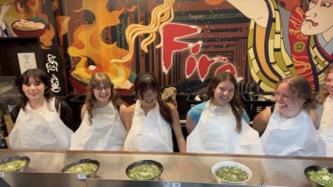 Four college students sitting in a ramen shop in Japan.