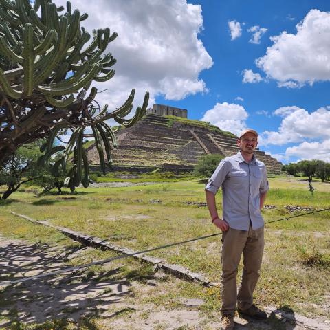 Alex standing in front of a pyramid, outside