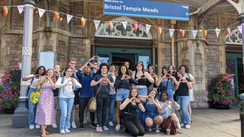 Group of University of Oregon students making an O shape with their hands at a train station in Bristol