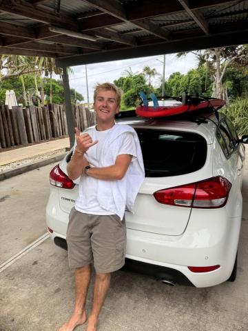 Calvin posing with a "hang loose" sign preparing to surf in Melbourne.