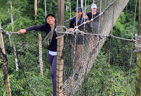 3 young woman crossing a suspended bridge in a jungle