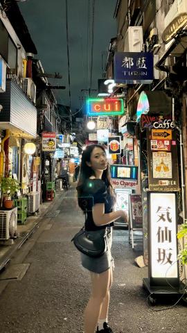 Evelyn smiling at night by shops on a street in Tokyo