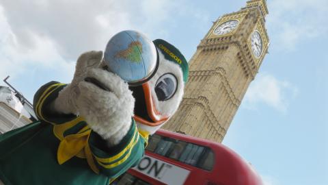 University of Oregon mascot holding a globe in front the the Big Ben