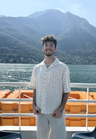 Luke stands on a boat with Lake Como in the background
