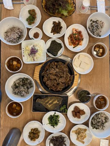 a table with about 20 plates of different sizes with various banchan (Korean side dishes)