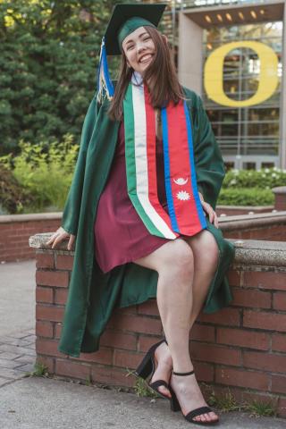 Woman with cap and gown and graduation sashes.