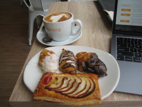 Plate of pastries and a cup of coffee on a table with a laptop.