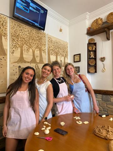 Four people smiling and posing together at a table with clay sculptures, in a room decorated with wooden artwork.