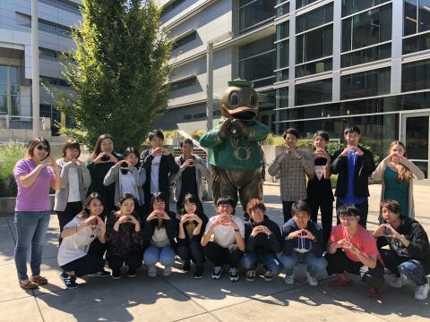Group of students throwing standing in front of the Oregon Duck statue