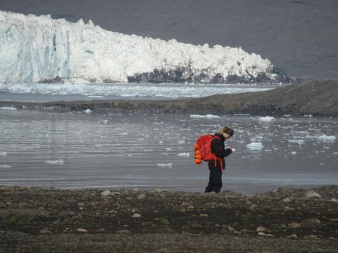 Maddy stands with a backpack, ice, water and land in the distance