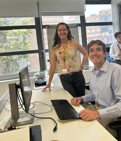 woman standing next to a desk where a college student is sitting in front of a computer
