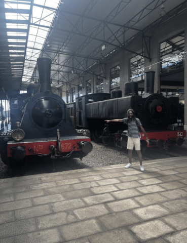 Jayden points at a black and red stationary passenger train in the background