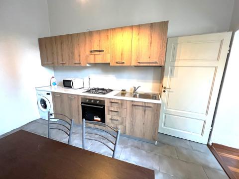 A small kitchen with brown cabinets and a brown table with two chairs 