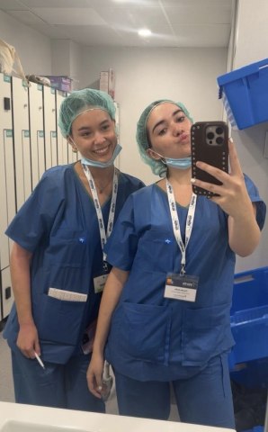 Two people in scrubs posing in a mirror
