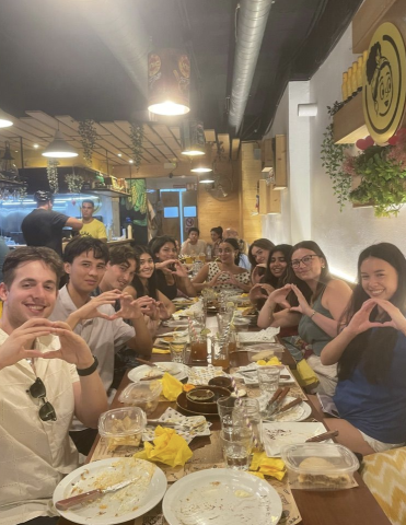 A long rectangular table in a restaurant with approximately 10 people on either side throwing their "O"