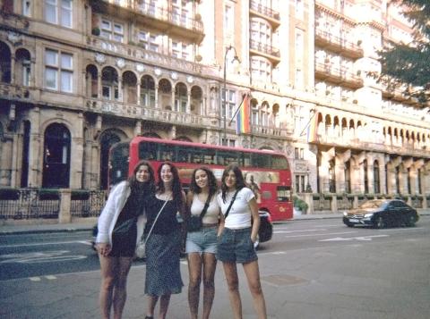 Group of 4 young women posing in front of a street in London with a red double decker bus in the background