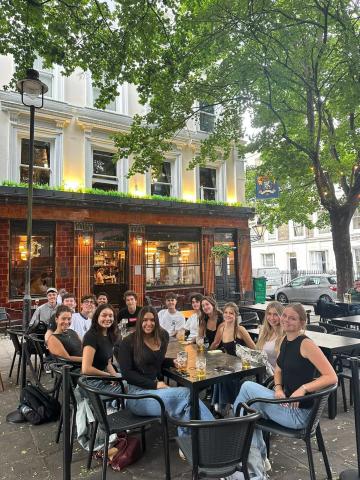 Cohort of GEO students sitting outside of a pub on a evening in London