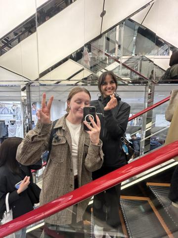 Zoe Tomlinson taking a mirror selfie with a friend on an escalator