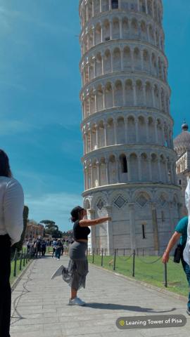 Girl posing in front of the Tower of Pisa, pretending to kiss it. 