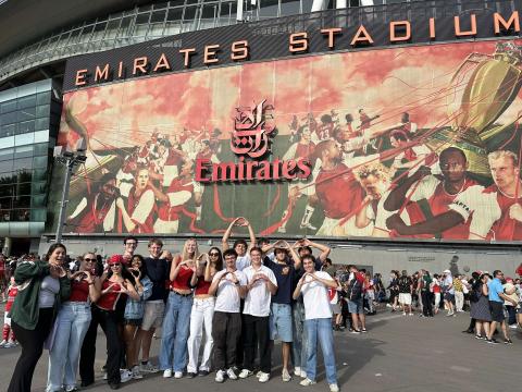 Group of people stands in front of the Emirates Stadium, throwing their "O"