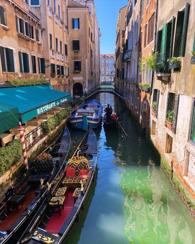 Shot of a man paddling a gondola through a canal in Italy.