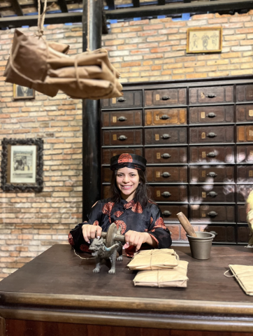 College-aged woman in traditional Vietnamese clothing smiling behind a wooden desk.  