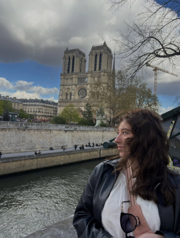 Student looking out to the distance on a boat ride on the river Seine with the Notre Dame Cathedral in the background.
