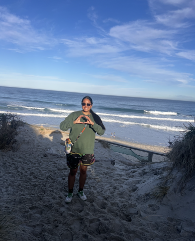 Keke posing with her hands in an "O" with a beach scene behind her