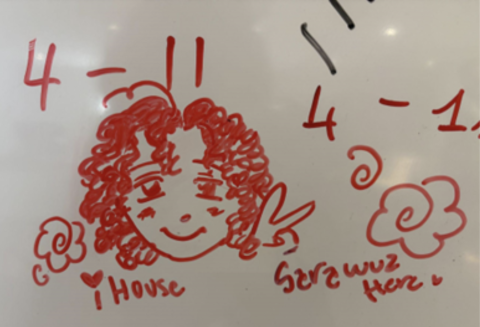 Whiteboard drawing in red ink; self portrait of Sara with words "IHouse" and "Sara wuz here"