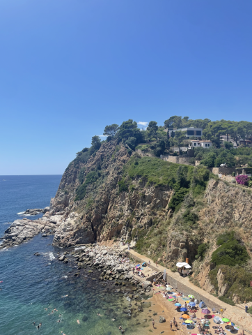 Beach with lots of people in the sand and a cliff in the distance