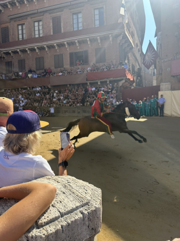Picture of a horse on a dirt track with people surrounding and cheering