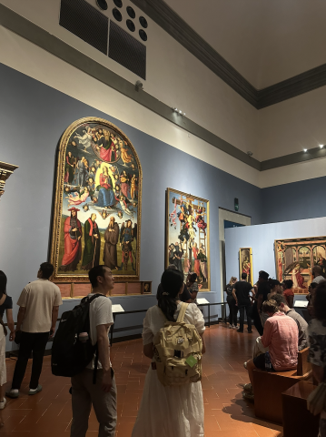 A painting hangs on a wall with spectators observing it