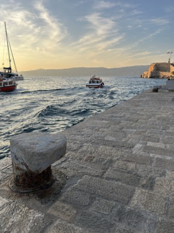 two boats are in the water at sunset with mountains behind them