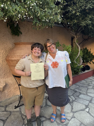 Will stands with a certificate next to someone else, they are both smiling