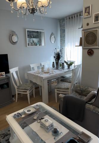 Small apartment living room with a white coffee table and white dining table and chairs, light blue walls with framed photos hung