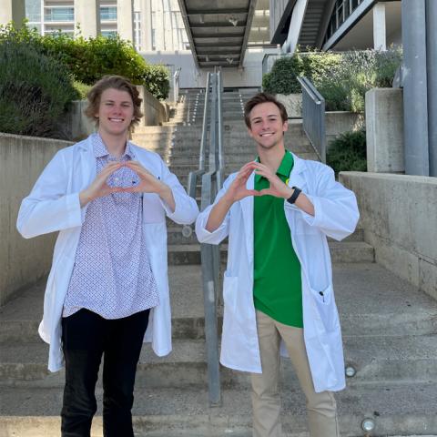 Two students wearing a lab coat throwing an O in Spain